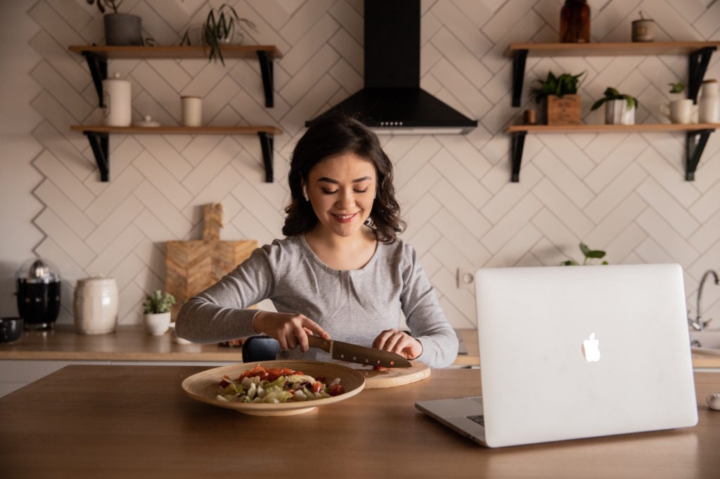 Woman eating food in front of laptop