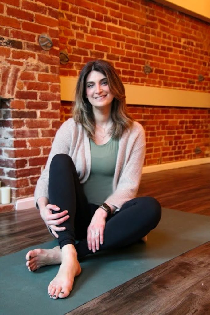 Ally Perleoni sitting on a yoga mat